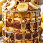 A slice of Banana Walnut Fudge Cake topped with nuts and fudge icing