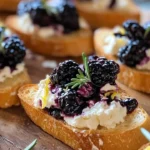 Blackberry goat cheese crostini topped with fresh blackberries and herbs