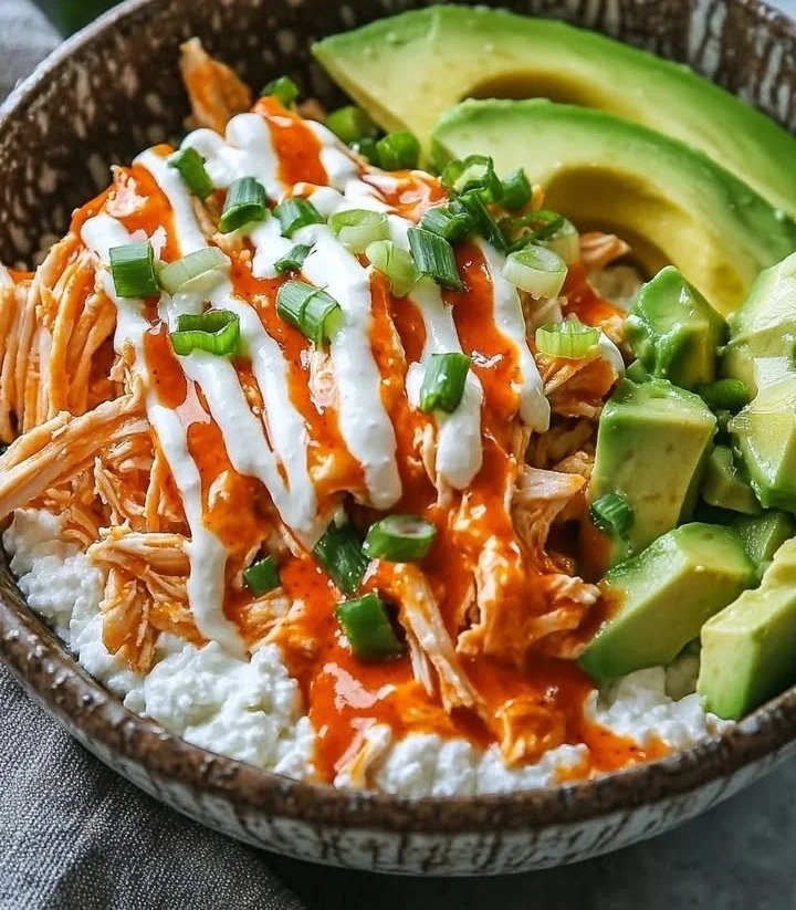 Buffalo Chicken Cottage Cheese Bowl topped with green onions and hot sauce
