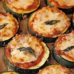 Cheesy zucchini pizza bites topped with melting cheese and fresh herbs