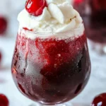 Refreshing Cherry Rum Coke Slushie in a glass with ice and cherries.