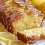 Lemon drizzle cake on a wooden table with a slice cut out