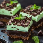 No-bake chocolate mint cheesecake bites on a plate with graham cracker crust.