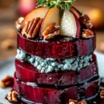 Roasted beet towers with blue cheese and garnishes served on a plate.