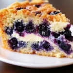 Sour cream blueberry coffee cake topped with fresh blueberries and a crumbly topping.