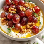 Whipped feta with roasted grapes, walnuts, and hot honey served on a platter